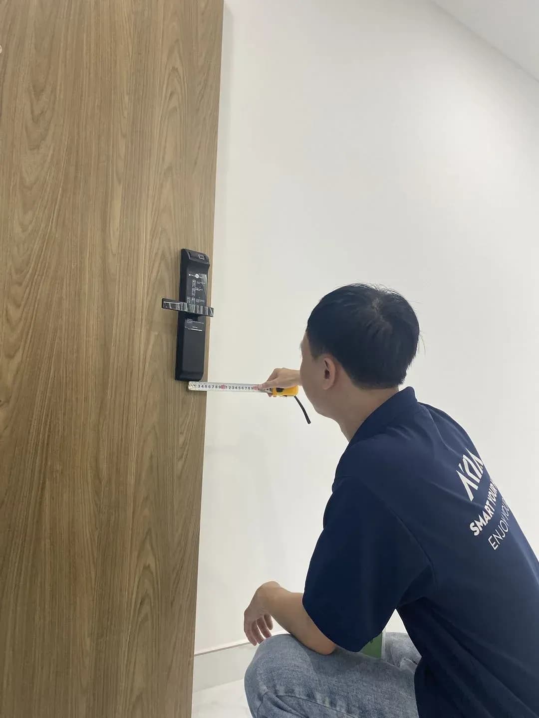 Kỹ thuật viên đang dùng thước đo kiểm tra vị trí lắp đặt khóa trên cửa gỗ